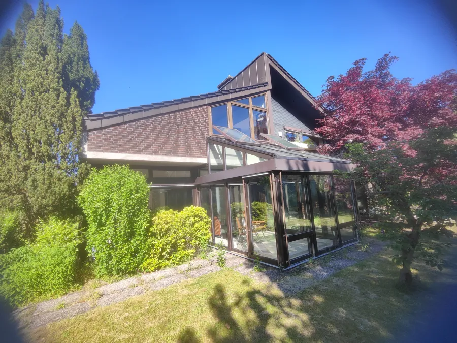 Südseite eines Zweifamilienhauses mit Wintergarten und großer Glasfront